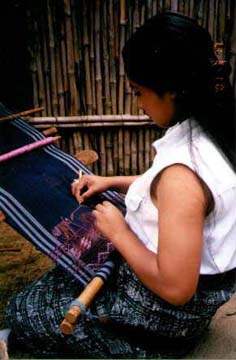 A young woman uses the aguja to lift warp threads so the weft threads can pass through. Copyright: Kennerley Clay.
