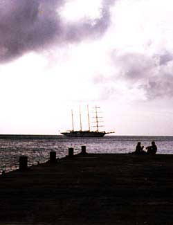 Dusk in Carriacou. A couple relax whlie a schooner sits at anchor. Copyright Jim Johnson.